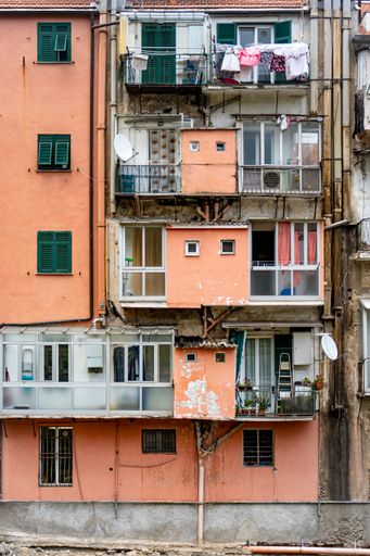 a vertical shot of an old pink residential building with balconies and hanging clothes