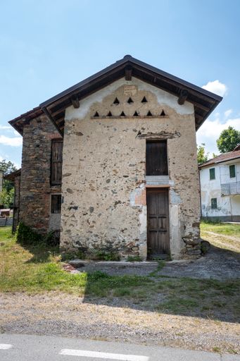 a vertical shot of an old house with a wooden door under sunlight