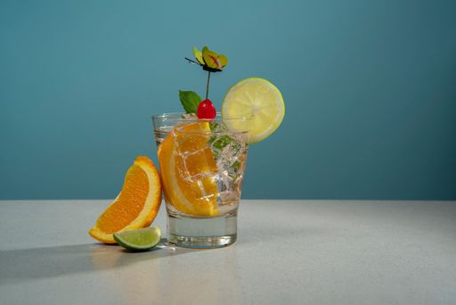 A glass of freshly squeezed orange juice with slices of citrus fruit on a wooden table
