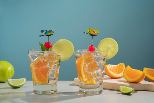 Two glasses of freshly squeezed orange juice with slices of citrus fruit on a wooden table