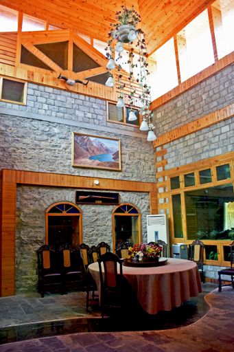 A vertical shot of the interior of an atmospheric restaurant with a round table and a wooden ceiling