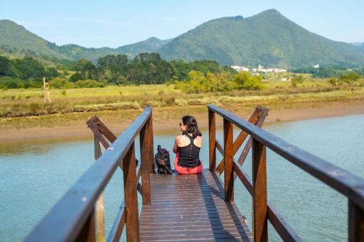 A young woman enjoying the scenery from the wooden piers of the Urdaibai marshes, a biosphere reserve in Bizkaia next to Mundaka. Basque Country