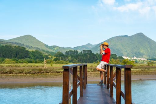A male watching birds with spyglasses from the wooden piers of the Urdaibai marshes