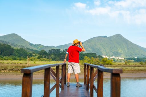A young man watching birds with spyglasses from the wooden piers of the Urdaibai marshes
