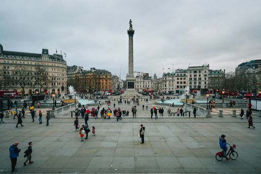The crowds strolling through the vast Trafalgar Square as the sun sets