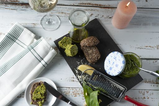 Freshly made wild garlic butter and pesto are served on wholemeal bread. In addition a candle and a glass of white wine