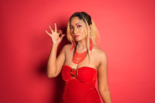 Woman in red dress making peace sign against red wall