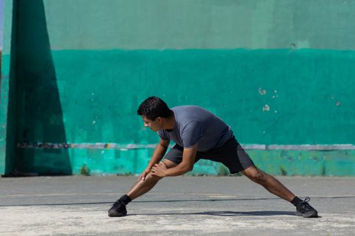 A Mexican young man stretching outdoors; urban exercise