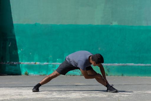 An athletic young male bending forward in the open air; urban exercise