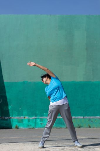 A Hispanic woman stretching outdoors, urban exercise