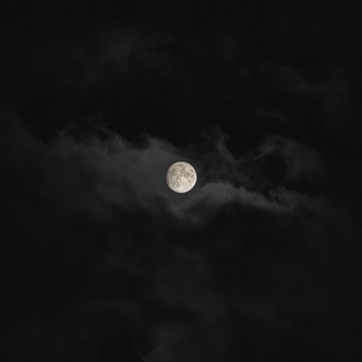 A low angle shot of the beautiful full moon in the cloudy sky