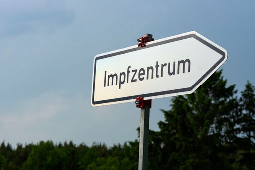 A selective focus of a road sign with a German text with vaccination center meaning showing the direction