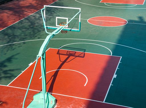 The open college basketball court, with bright colors, is illuminated by the warm noon sunshine