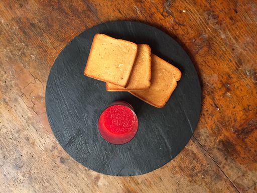 A top view shot of a strawberry jam and toasts on a wooden table