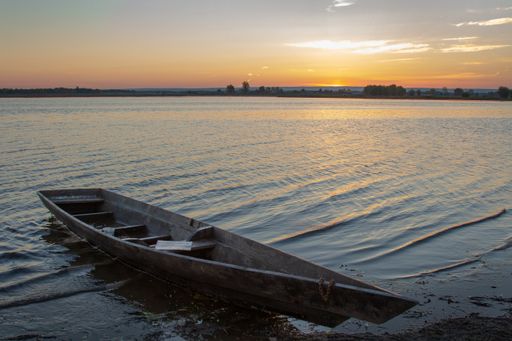 Sunrise on the lake. Small waves rock the lonely boats.