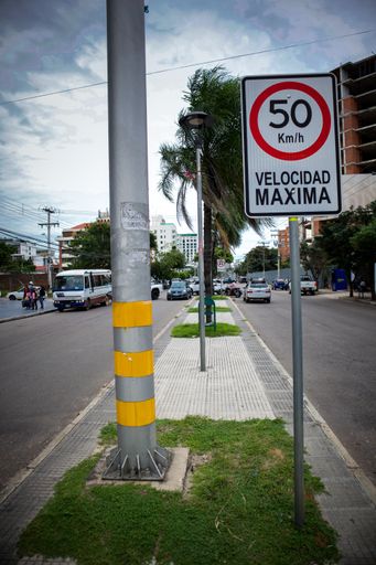 A vertical shot of a speed limit sign in the middle of a boulevard