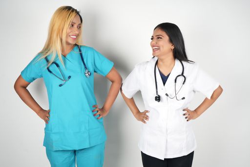Two female nurses conversing near a white wall