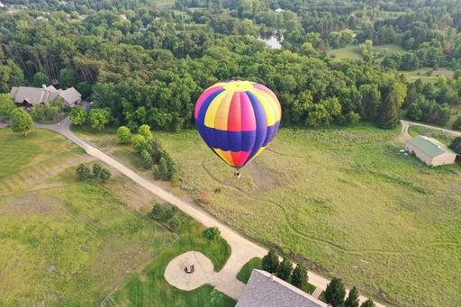 Hot air balloon soaring above a quaint village nestled amidst lush greenery