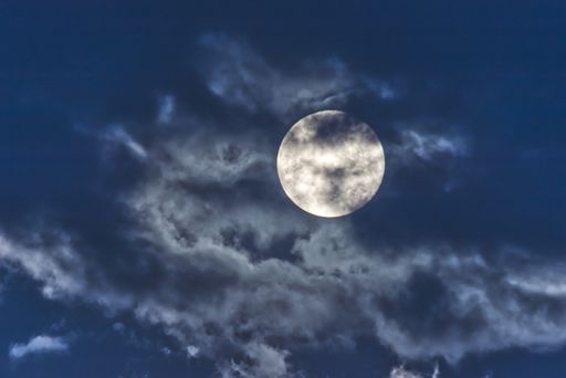 A closeup shot of the full moon on a cloudy sky