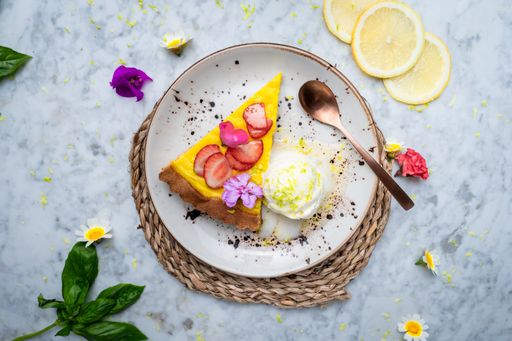 A Top view of a plate with Vegan No-bake cheesecake toped with a strawberry on the side cashew cream