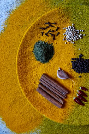 A top view of various spices on a half yellow plate with grunge background.
