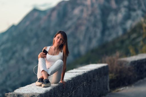 A young Caucasian female listening to music on the phone and enjoying the nature in Montenegro