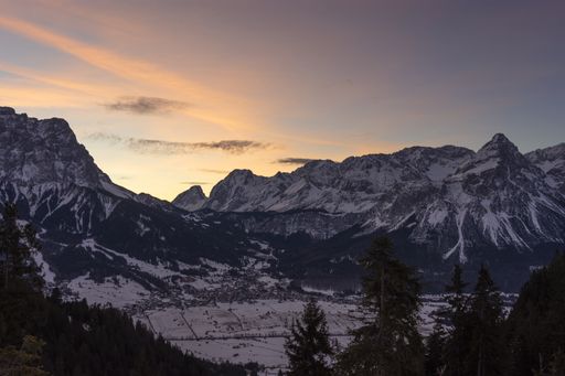 Dawn at the mountain village Ehrwald in winter. Landscape with snowy rocky mountains and colorful sky. Tirol, Austria