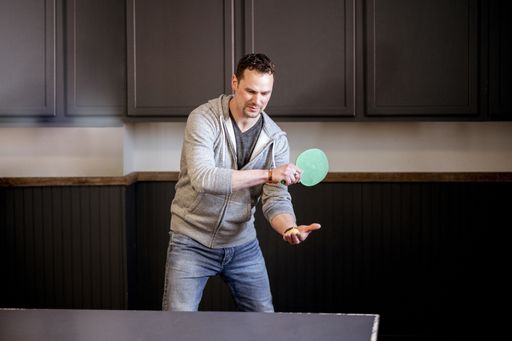 A young Caucasian male playing table tennis during daytime