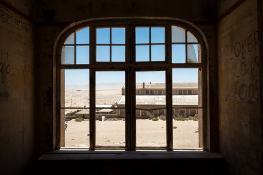 An aged, dilapidated room with a big window in an old desert town