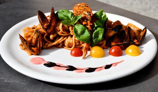 A closeup shot of tasty seafood pasta with fresh basil and cherry tomatoes on a white plate