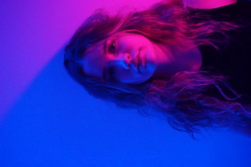 A vertical shot of a white Caucasian girl posing for a picture on a colorful background