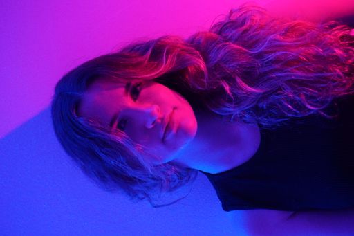 A vertical shot of a white Caucasian girl posing for a picture on a colorful background