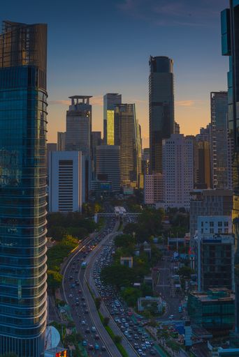 City skyline with traffic in foreground at sunset, featuring a busy highway