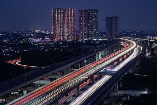 A drone shot of the long exposures of car light trails entering Jakarta from the Bekasi Highway Railway at night, Indonesia
