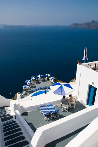 A terrace with chairs and umbrellas overlooking the waterfront in Santorini, Greece.
