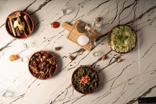 An overhead shot of four plates with salads on a marble background