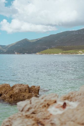 A vertical shot of a rocky seashore of Parque Natural da Arrabida on a sunny day