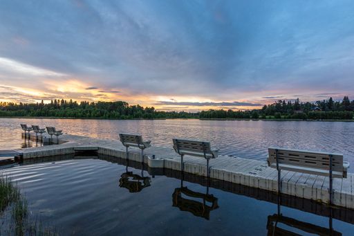 A beautiful sunset over the big pier with dock benches reflecting in a clear water