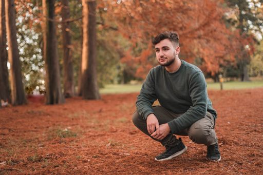 A young attractive man crouched in a park