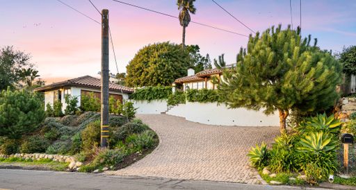 Beautiful suburban house with a lush driveway adorned with vibrant plants and illuminated by a charming street light
