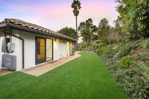 A spacious backyard with a verdant lawn and lush trees