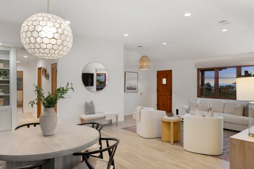 A pristine dining and living space with wooden floors in a white color scheme