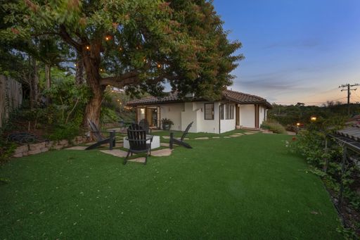 A spacious backyard with a green lawn and sitting area