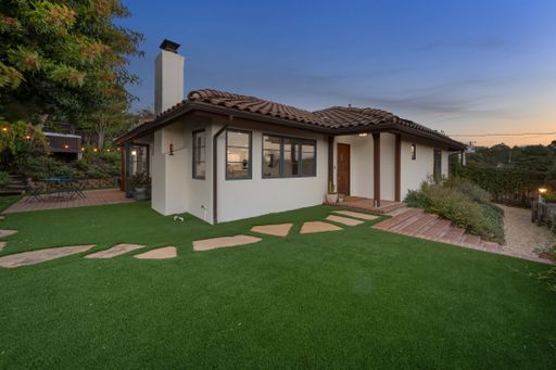 A spacious backyard with a verdant lawn and lush trees