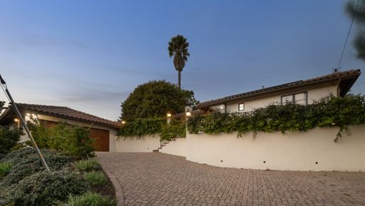 A house driveway with a stone wall adorned with lush greenery