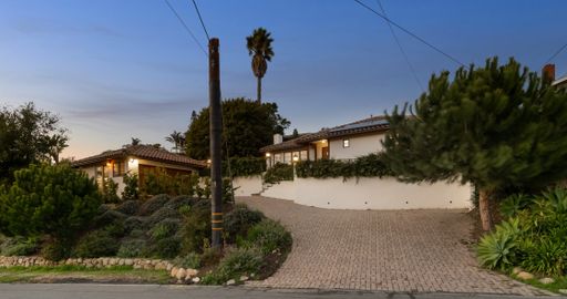 A house driveway with a stone wall adorned with lush greenery