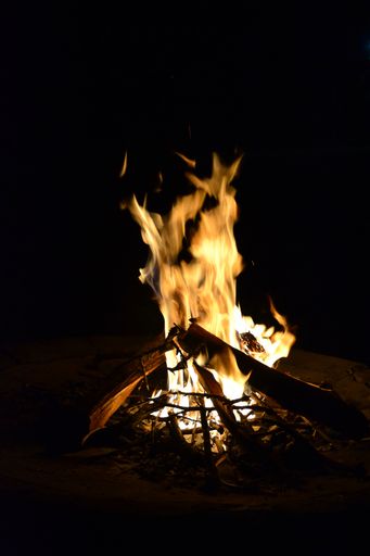 A vertical shot of a burning bonfire outdoors in the dark