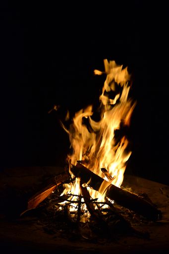 A vertical shot of a burning bonfire outdoors in the dark