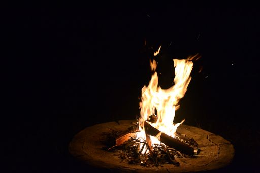 A closeup of a burning bonfire outdoors in the dark