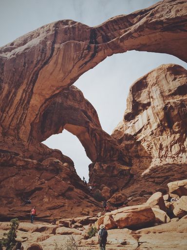 A vertical low angle shot of the double arch at arches national park on a sunny day